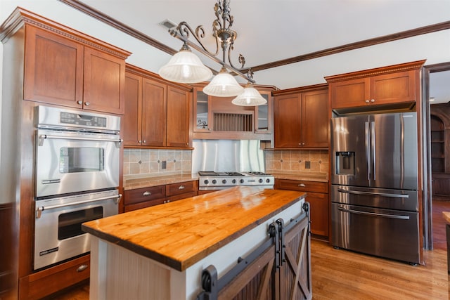 kitchen featuring pendant lighting, wooden counters, appliances with stainless steel finishes, and a center island