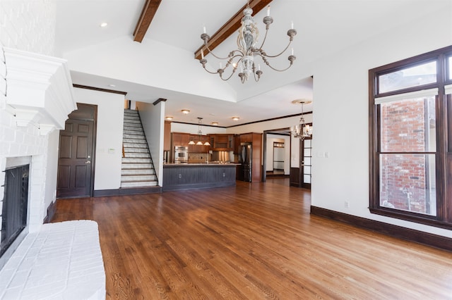 unfurnished living room featuring a brick fireplace, a chandelier, beam ceiling, and hardwood / wood-style flooring