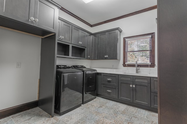 washroom with ornamental molding, washing machine and clothes dryer, sink, and cabinets