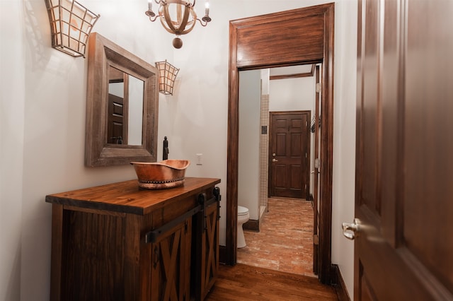 corridor featuring sink, a chandelier, and dark hardwood / wood-style floors