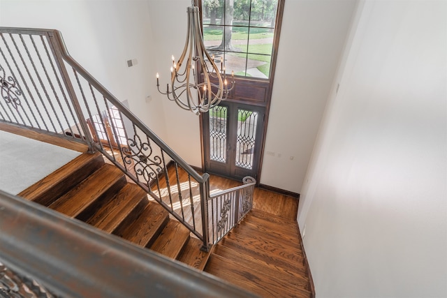 stairway featuring an inviting chandelier, hardwood / wood-style flooring, and french doors