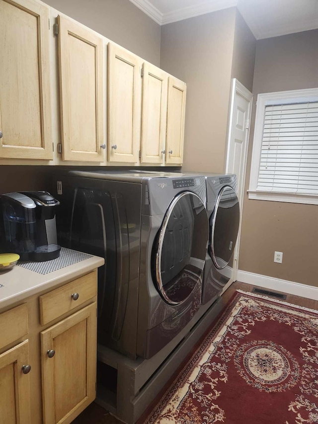 clothes washing area featuring ornamental molding, cabinets, and washer and dryer