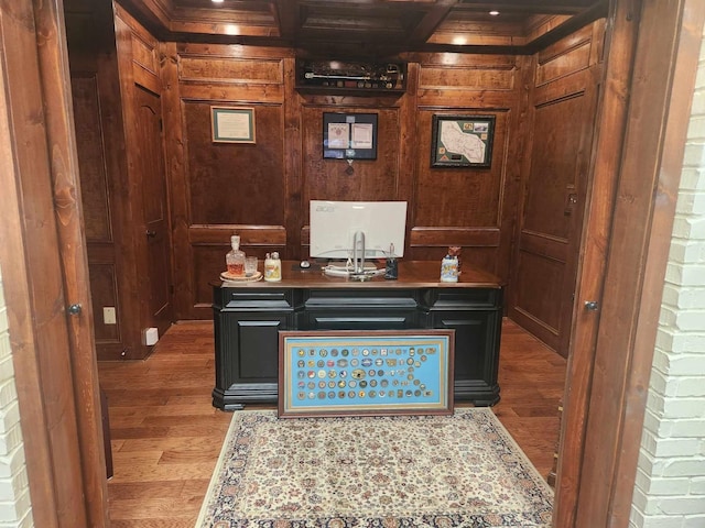 office area with wood-type flooring, beam ceiling, coffered ceiling, and wooden walls