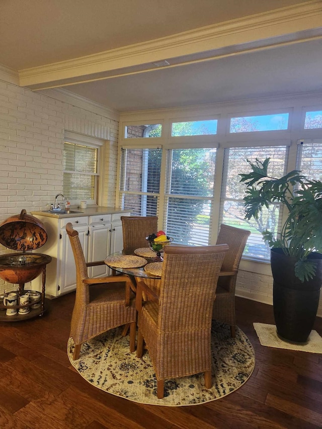 dining room with crown molding, a wealth of natural light, dark wood-type flooring, and brick wall