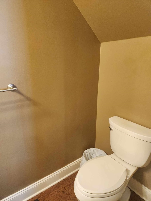 bathroom featuring hardwood / wood-style flooring, toilet, and vaulted ceiling