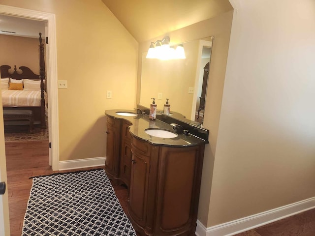 bathroom with hardwood / wood-style floors, vanity, and vaulted ceiling