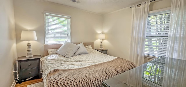 bedroom with a textured ceiling, hardwood / wood-style flooring, and ornamental molding