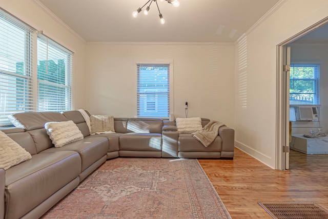 living room with cooling unit, crown molding, light wood-type flooring, and a healthy amount of sunlight