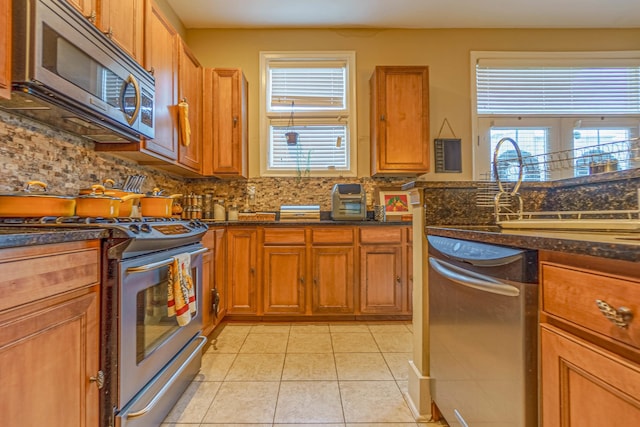 kitchen with stainless steel appliances, light tile patterned flooring, decorative backsplash, and a wealth of natural light