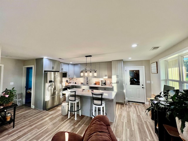 kitchen with gray cabinets, appliances with stainless steel finishes, hanging light fixtures, and a center island