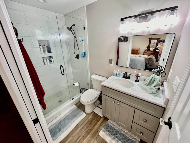 bathroom with hardwood / wood-style floors, toilet, walk in shower, and vanity