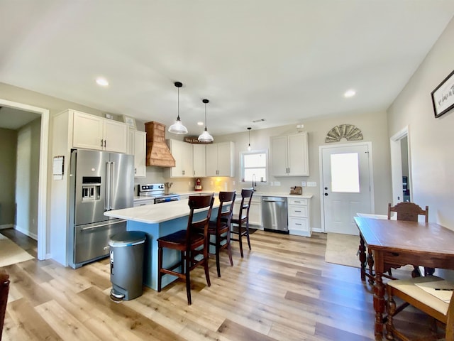 kitchen with pendant lighting, custom range hood, stainless steel appliances, a center island, and white cabinetry