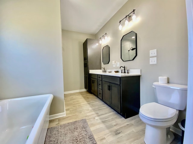 bathroom featuring hardwood / wood-style floors, a washtub, vanity, and toilet