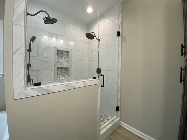 bathroom with a shower with door and wood-type flooring