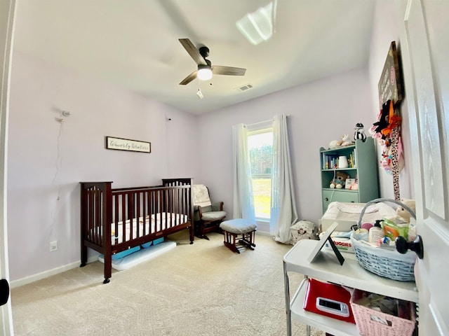 carpeted bedroom with a nursery area and ceiling fan