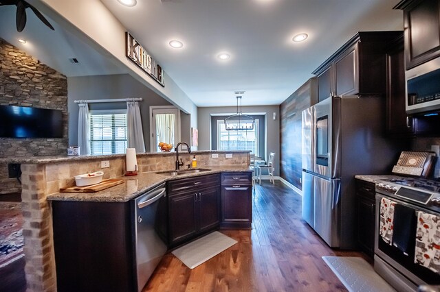 kitchen featuring dark hardwood / wood-style flooring, dark brown cabinets, sink, hanging light fixtures, and appliances with stainless steel finishes