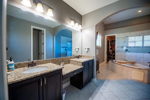 bathroom featuring tile patterned flooring, vanity, and tiled bath