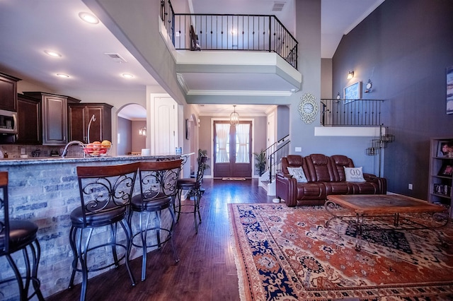 interior space with crown molding, a towering ceiling, dark hardwood / wood-style floors, and french doors