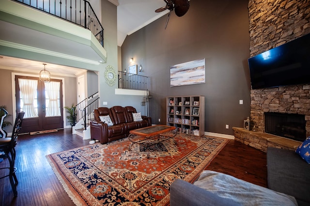 living room featuring a high ceiling, ceiling fan, crown molding, dark wood-type flooring, and french doors