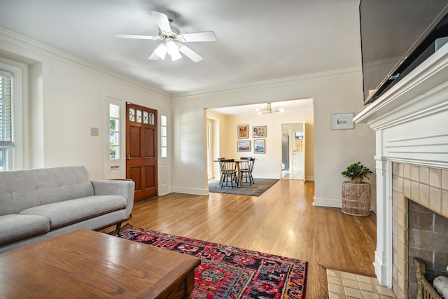 living room featuring light hardwood / wood-style flooring, a tiled fireplace, and ornamental molding