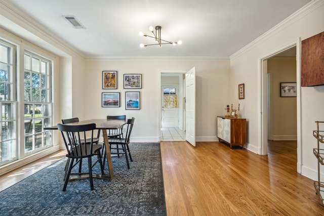 dining area featuring wood-type flooring, ornamental molding, and a notable chandelier