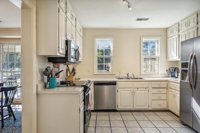 kitchen with appliances with stainless steel finishes, a healthy amount of sunlight, sink, and light tile patterned floors