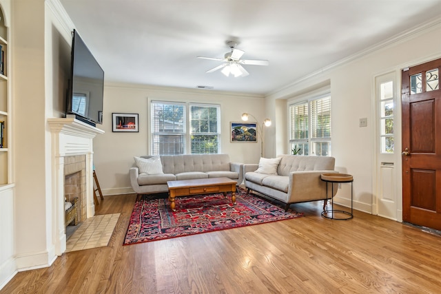 living room with crown molding, light wood-type flooring, a wealth of natural light, and a tile fireplace