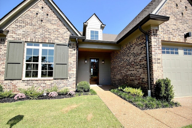 entrance to property featuring a yard and a garage