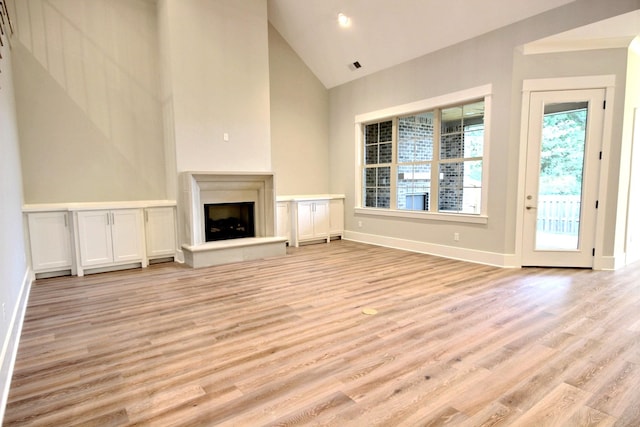 unfurnished living room featuring light wood-type flooring and high vaulted ceiling