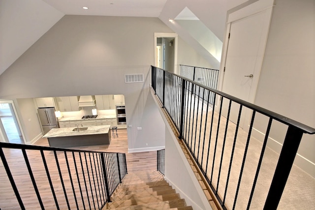 stairway featuring hardwood / wood-style flooring, high vaulted ceiling, and sink