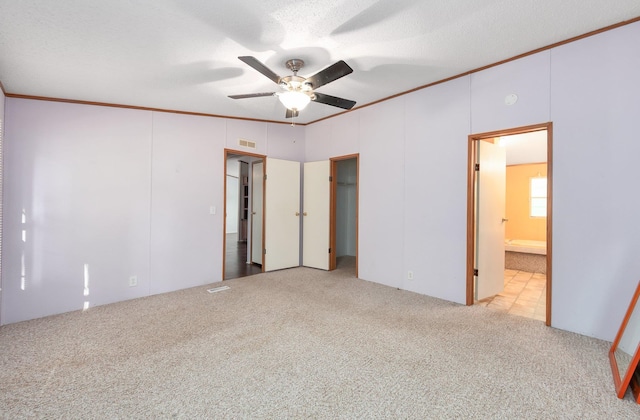 unfurnished bedroom with ceiling fan, a textured ceiling, connected bathroom, and light carpet