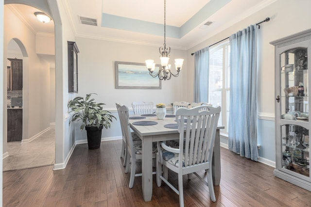 dining room with a tray ceiling, dark hardwood / wood-style floors, a chandelier, and crown molding