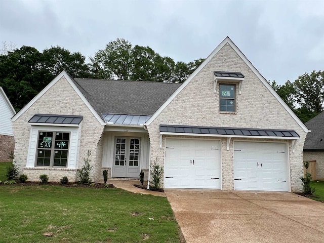 view of front of house featuring a standing seam roof, french doors, concrete driveway, a front lawn, and roof with shingles