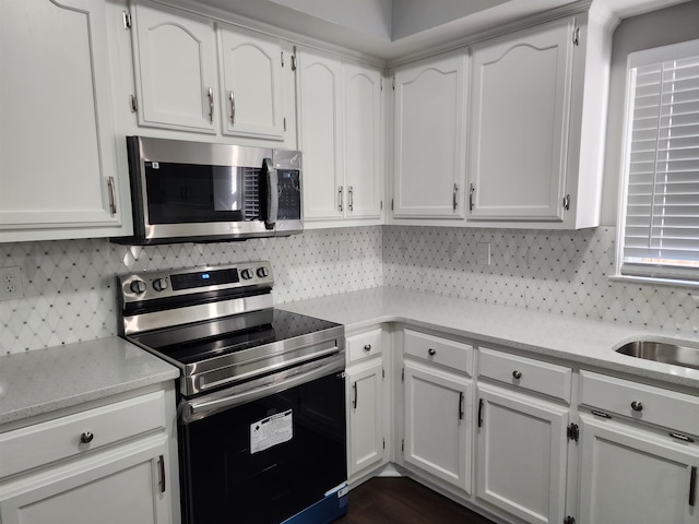 kitchen with decorative backsplash, stainless steel appliances, and white cabinets