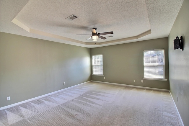 carpeted spare room with a tray ceiling, a textured ceiling, and ceiling fan