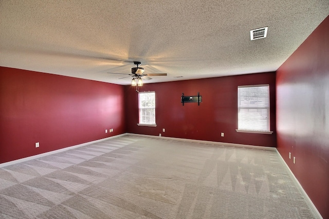 empty room with ceiling fan, a textured ceiling, and light carpet