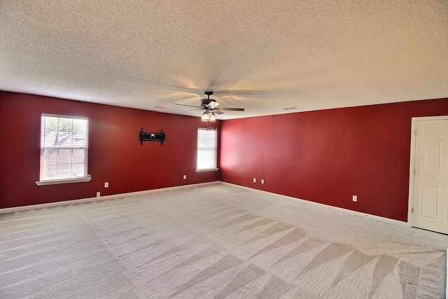 unfurnished room featuring ceiling fan, a textured ceiling, light carpet, and a healthy amount of sunlight