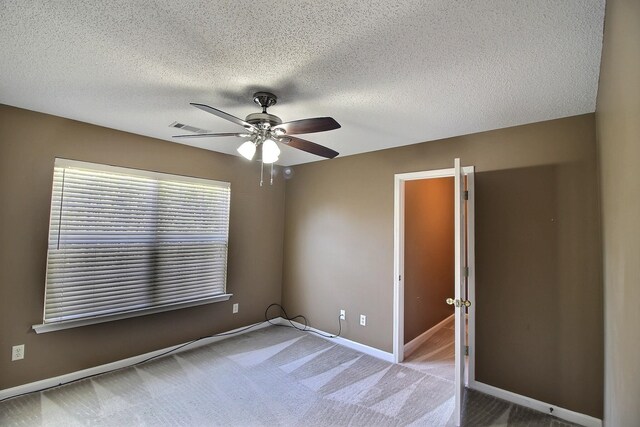 empty room featuring ceiling fan, a textured ceiling, and carpet