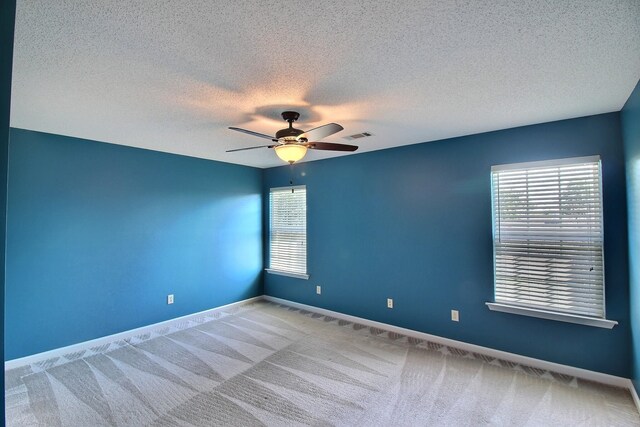 carpeted spare room featuring ceiling fan and a textured ceiling