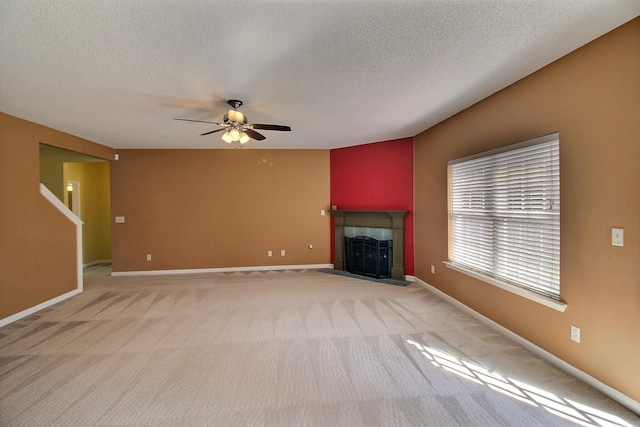 unfurnished living room with ceiling fan, light colored carpet, a textured ceiling, and a fireplace