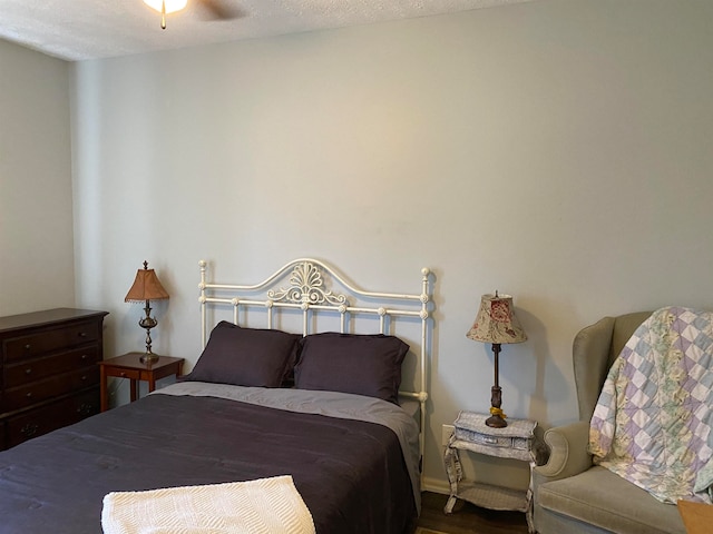 bedroom with a textured ceiling, hardwood / wood-style flooring, and ceiling fan