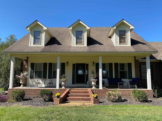 new england style home featuring a porch and a front lawn