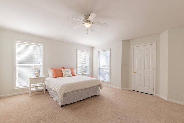 bedroom with ceiling fan, light carpet, and multiple windows