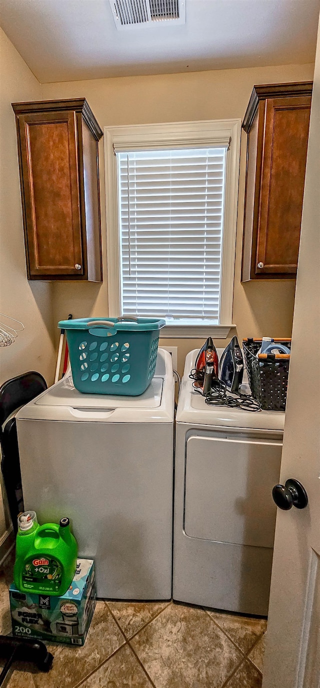 clothes washing area featuring light tile patterned flooring, washer and clothes dryer, and cabinets