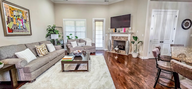 living room featuring a premium fireplace, dark hardwood / wood-style flooring, and crown molding