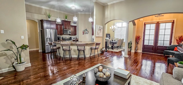 living room with dark hardwood / wood-style floors, an inviting chandelier, ornamental molding, and sink