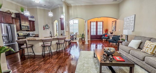 living room with crown molding, a high ceiling, dark hardwood / wood-style flooring, and sink