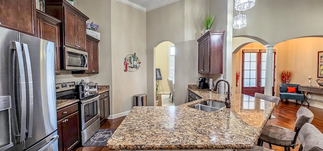 kitchen with appliances with stainless steel finishes, dark hardwood / wood-style floors, sink, and dark stone counters