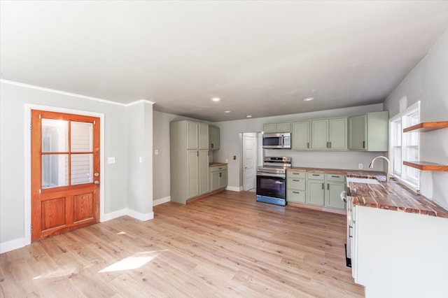 kitchen with green cabinetry, butcher block counters, sink, light hardwood / wood-style floors, and appliances with stainless steel finishes