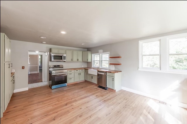 kitchen with green cabinetry, light hardwood / wood-style floors, a wealth of natural light, and stainless steel appliances